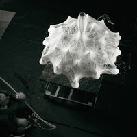White, textured round parasol with intricate patterns, set against a dark background. Unique design for outdoor decor.