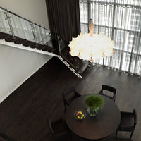 Chic white chandelier above a dark wood table, contrasted with soft cream curtains and modern black chairs.