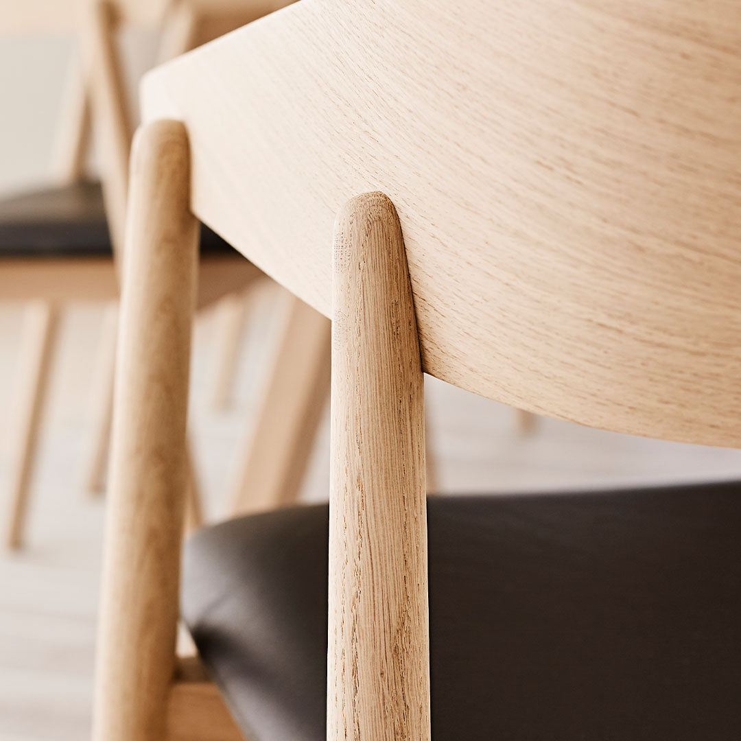 Light natural wood grain contrasts with dark leather upholstery, showcasing a sleek, modern design.