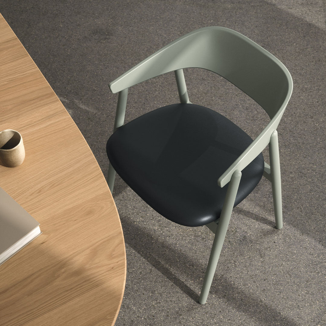 Green and black contemporary chair with a sleek design against a wood and gray background. Ideal for modern spaces.