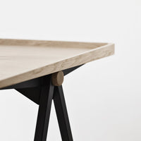 Light wooden tabletop with a natural finish, accented by sleek black metal legs, minimalistic design.