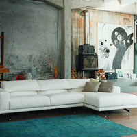 Modern white sectional sofa on a teal area rug, featuring a minimalist design and subtle textured patterns.