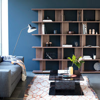 Modern wooden shelving in warm walnut tones, paired with a geometric patterned rug in orange and cream.