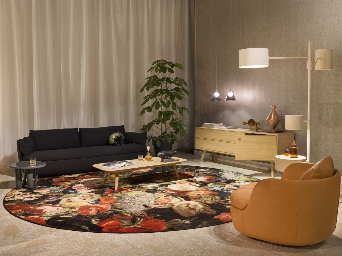 "Round floral rug featuring rich reds, yellows, and greens against a dark background, complementing modern decor."