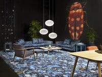 Blue floral patterned rug with dark background, complemented by a blue sofa and elegant pendant lights. Modern decor.
