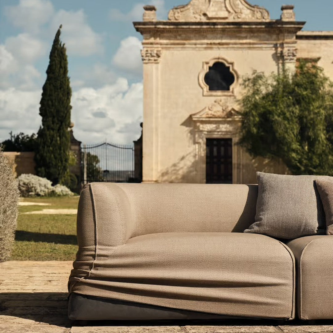 Beige outdoor sofa with minimalist design and smooth fabric, featuring a soft, relaxed silhouette.