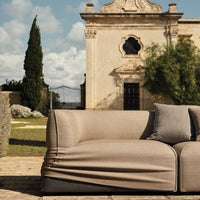 Beige outdoor sofa with minimalist design and smooth fabric, featuring a soft, relaxed silhouette.