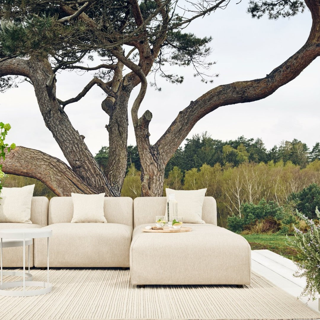 Beige sectional sofa with a textured fabric, complemented by neutral cream cushions, set against a natural backdrop.