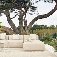 Beige sectional sofa with a textured fabric, complemented by neutral cream cushions, set against a natural backdrop.