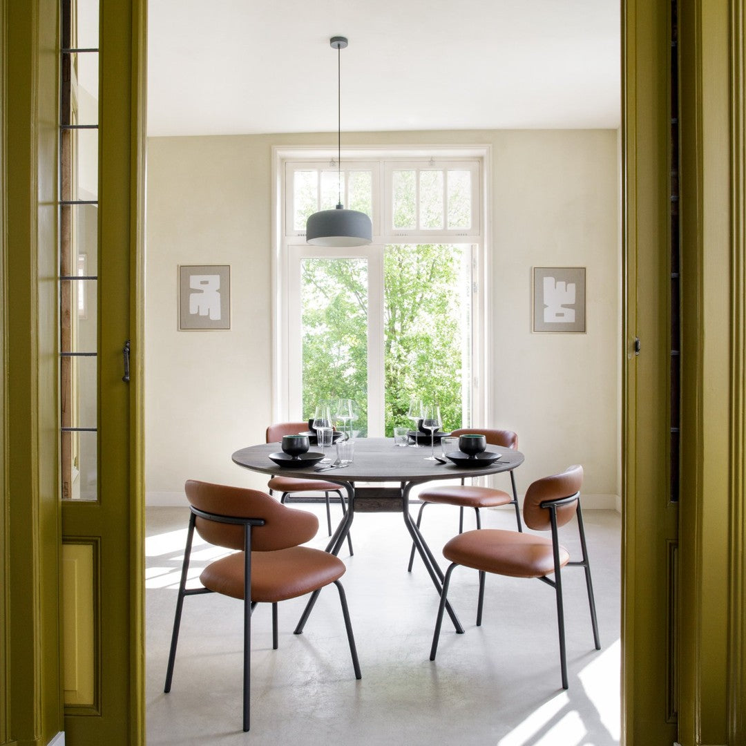 Elegant dining room featuring light beige walls, green door frames, and modern black and orange tones in furniture.