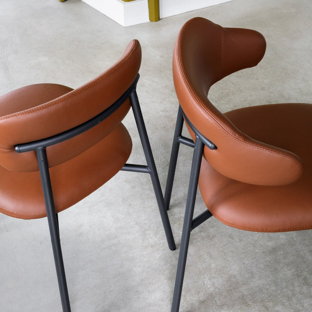 Brown leather chairs with a smooth finish and black metal frames, featuring a modern, minimalist design.