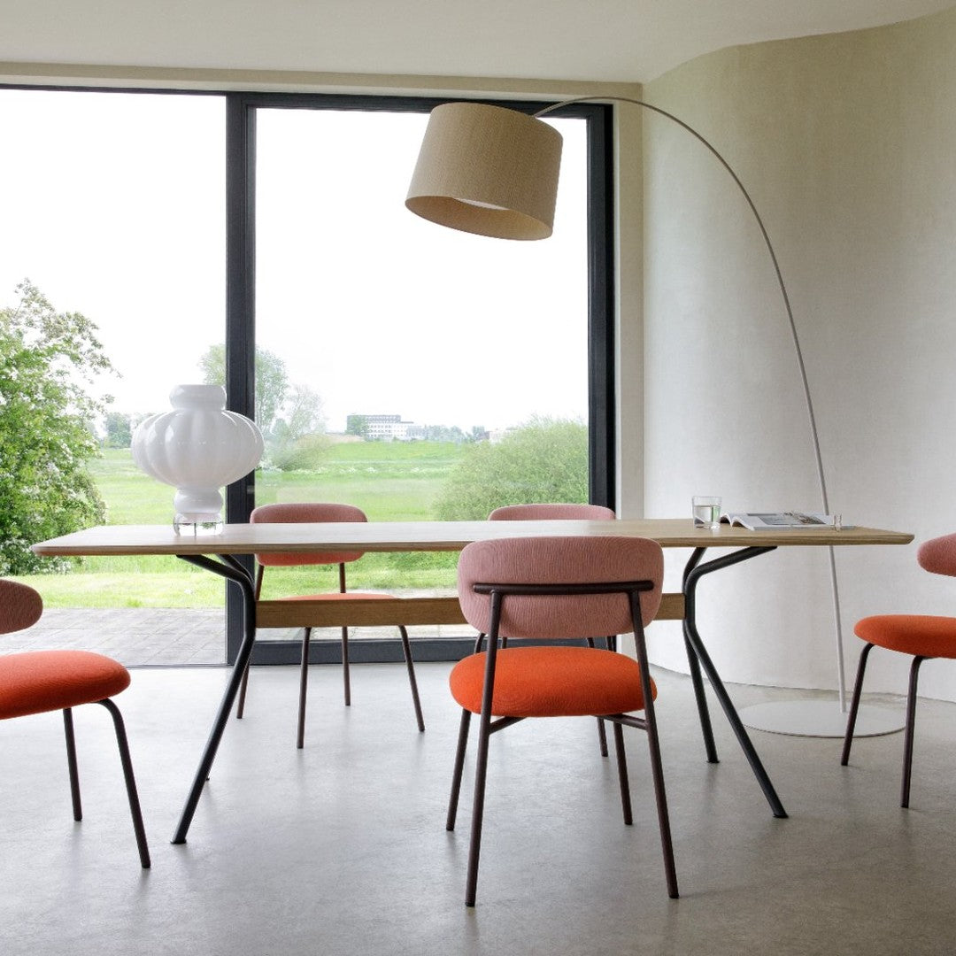 Modern dining table scene featuring soft pink and vibrant orange chairs against a serene, neutral backdrop.