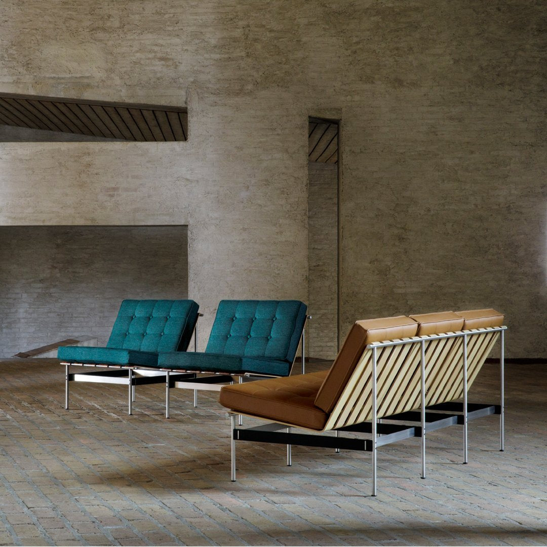 Teal and brown tufted sofas with sleek metallic frames in a modern minimalist space.