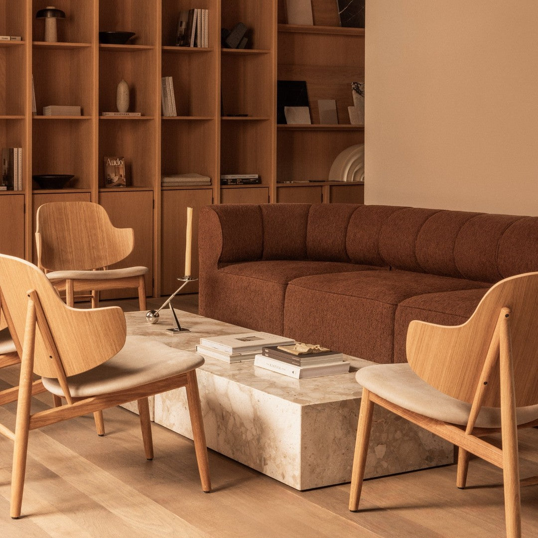 "Elegant brown sofa with light wooden chairs and a beige marble coffee table, set against a warm neutral backdrop."