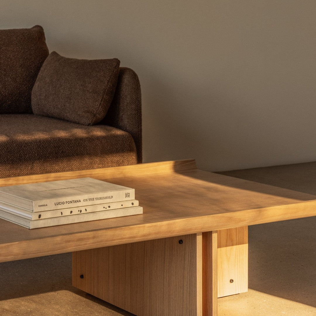 Brown fabric sofa with light wooden coffee table; minimalistic design showcasing natural wood tones and soft shadows.
