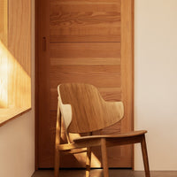 Natural wood chair with light brown tones and smooth grain pattern, set against a warm, minimalist backdrop.
