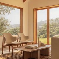 "Neutral beige chairs with soft curves and natural wood accents, paired with a light wooden coffee table in a serene setting."