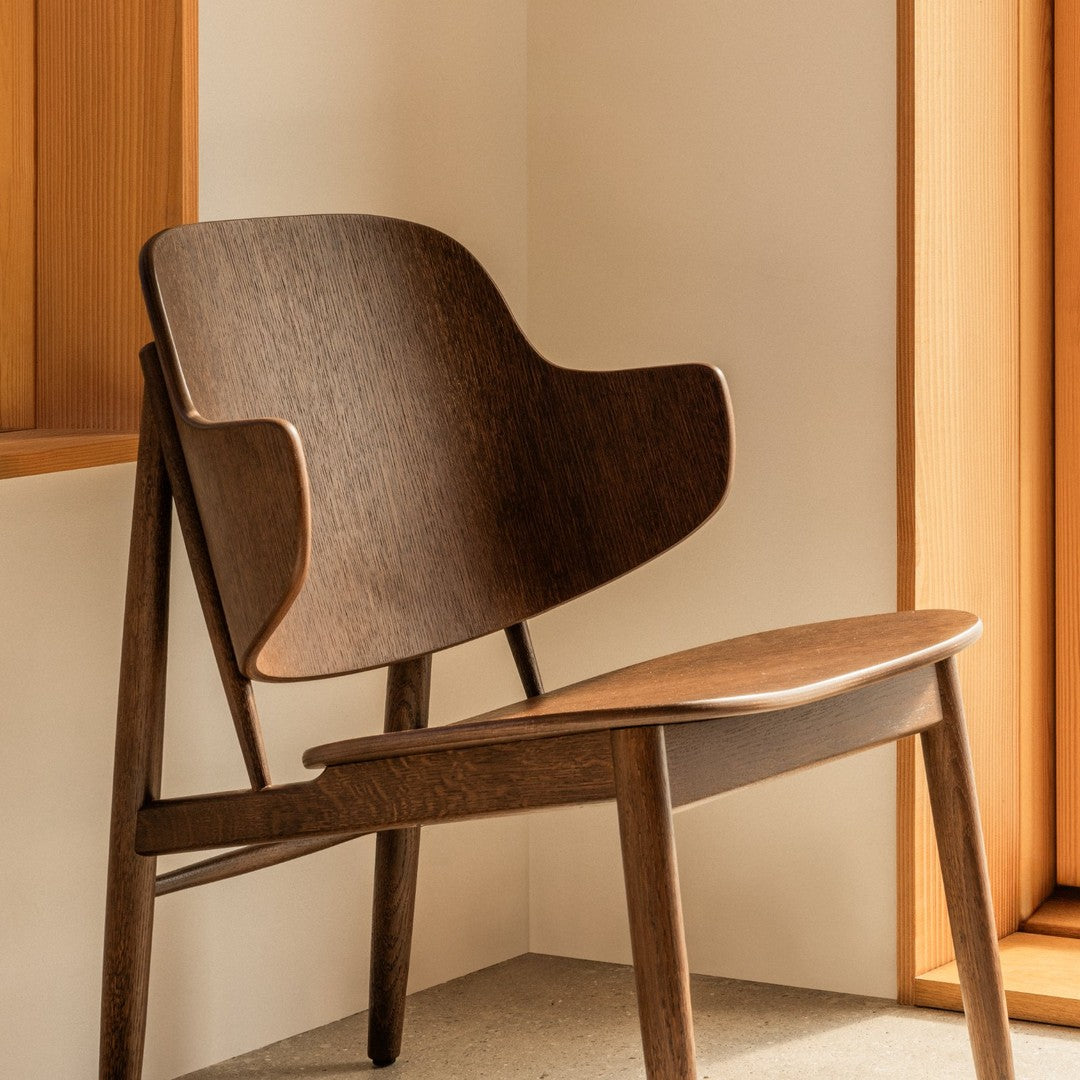 Mid-century modern chair in rich brown wood with smooth, minimalist lines and natural finish.