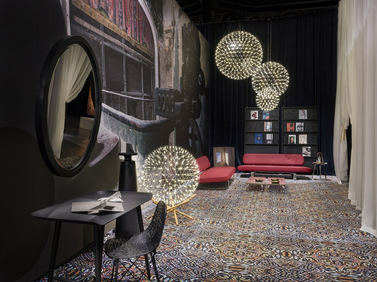 Colorful patterned rug with intricate designs, complemented by red furniture and round, glowing pendant lights.