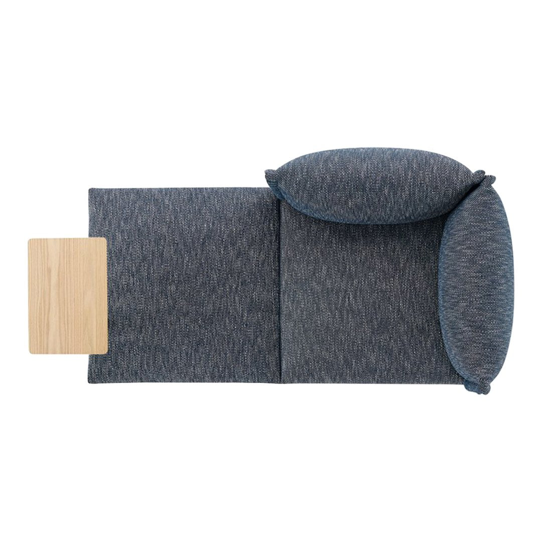 Slate blue sofa with textured upholstery and matching round cushions, complemented by a light wood side table.