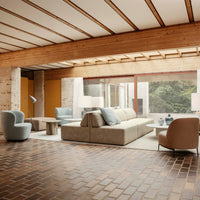 Modern living room with beige sofa, blue and gray chairs, and natural wood accents, featuring a geometric floor pattern.