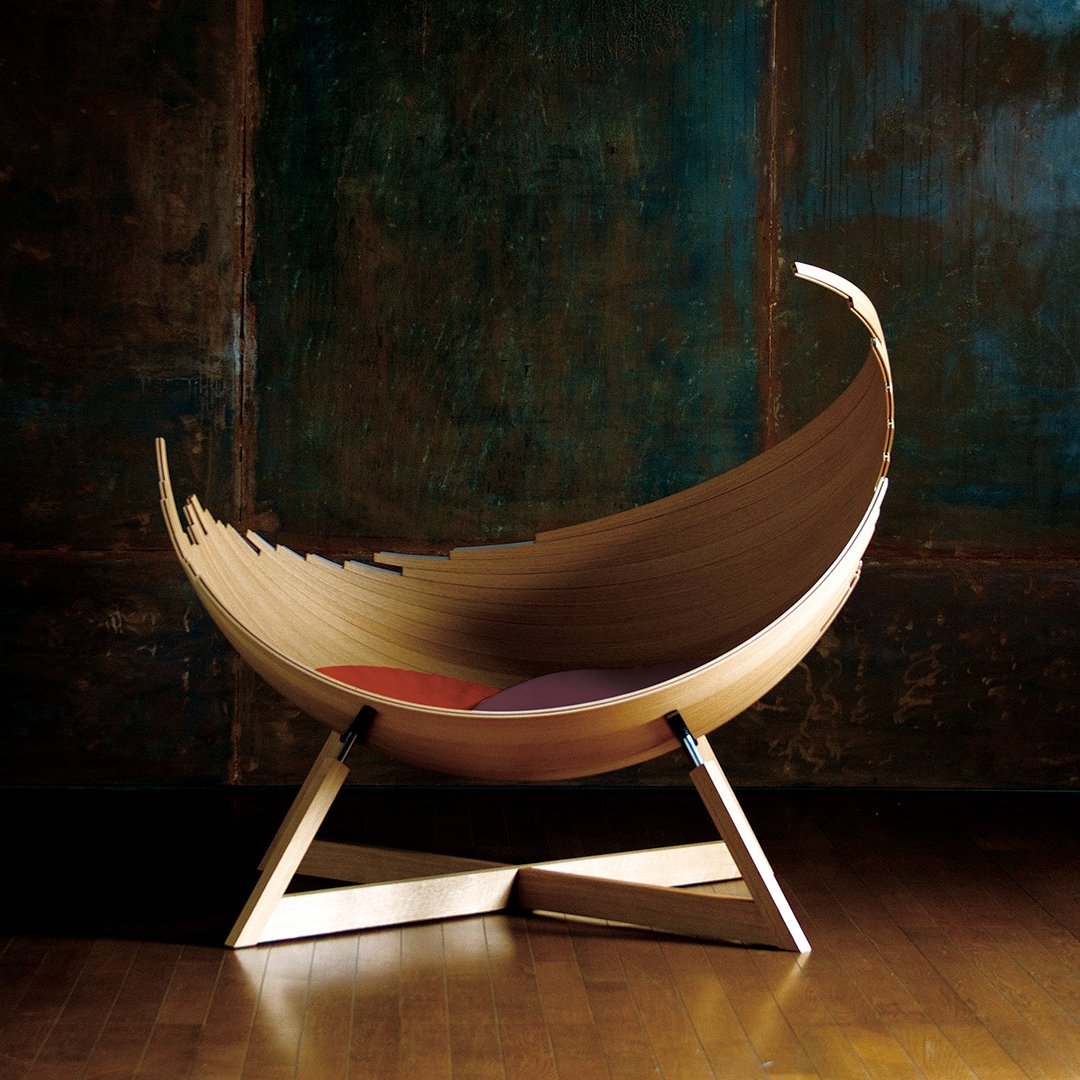 Sleek wooden chair with smooth curves, featuring earthy tones and pops of vibrant red and purple.