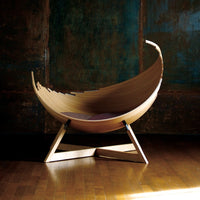 Natural wood finish with a smooth, curved design; complementary soft purple cushion against a textured backdrop.