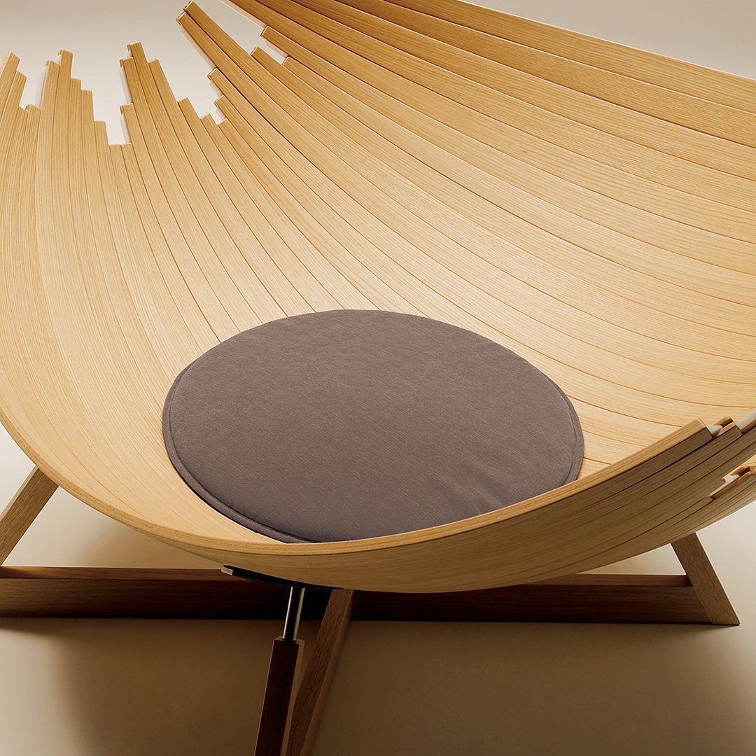 Curved wooden chair with a natural finish and a round gray cushion for comfort. Modern design with minimalistic patterns.
