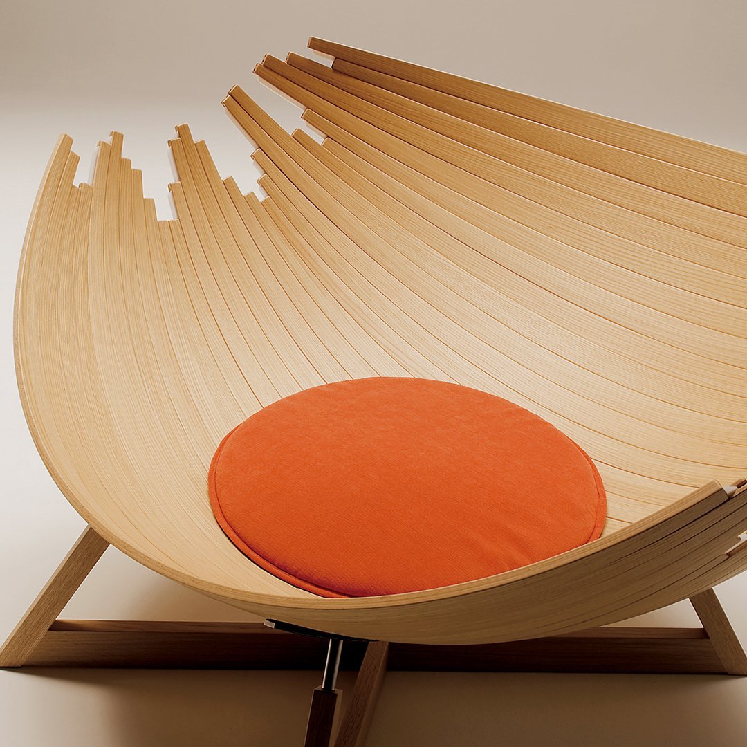Curved wooden lounge chair featuring a natural finish and vibrant orange cushion for a modern aesthetic.