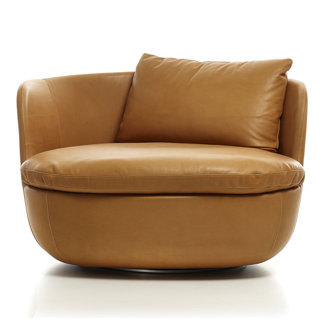 Tan leather armchair with a smooth, minimalist design and a plush, removable cushion for added comfort.