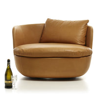 Warm tan leather accent chair with a smooth, curved design and plush cushions. Ideal for modern interiors.