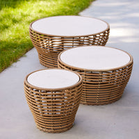 Natural rattan coffee tables in varying sizes, featuring woven patterns and light-colored round tabletops.
