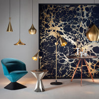 Elegant turquoise chair with gold and black pendant lamps against a navy and gold marbled wall pattern.