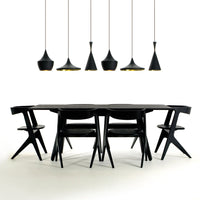 Sleek black dining table and chairs with modern black pendant lights, featuring minimalist shapes and an elegant design.