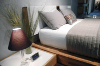 Stylish bedroom scene featuring gray pillows, a taupe quilt, and a sleek wooden bed frame.