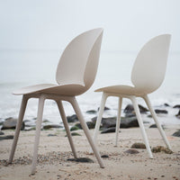 Neutral-toned chairs in soft beige and off-white, featuring a minimalist design against a sandy beach backdrop.