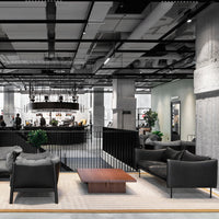 Modern black sofas paired with a warm wood coffee table in a stylish open space with concrete and greenery accents.