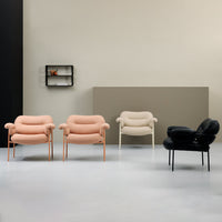 "Pair of blush pink, plush armchairs with curved forms and copper legs against a soft neutral backdrop."