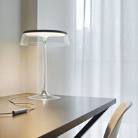 Transparent table lamp with a sleek black shade, minimalist design, and a clear base on a modern desk.
