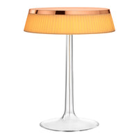 Modern table lamp with a clear base, orange pleated shade, and rose gold rim accent. Ideal for stylish decor.