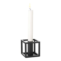 Black square candle holder with a tall white candle, minimalistic design. Ideal for modern decor.