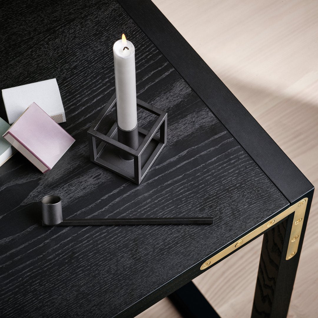 Elegant black wooden table with geometric patterns, featuring gray and pastel-colored candle holder and accessories.