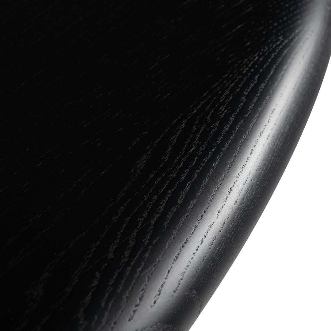 Close-up of a sleek black wood surface with subtle grain patterns and a glossy finish.