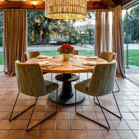 Elegant green velvet dining chairs with a rustic wooden table and warm earthy tones in a stylish indoor setting.