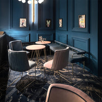 Elegant blue walls with gold accents, soft pink chairs, and a patterned rug create a stylish seating area.