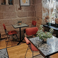Stylish black and white floral pattern on tabletops with red upholstered chairs in a cozy setting.