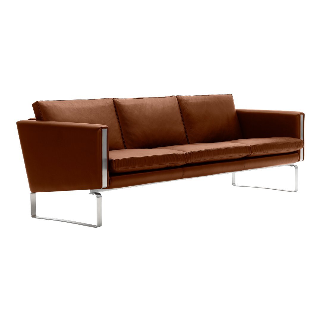 Brown leather sofa with sleek chrome legs, featuring a minimalist design and smooth, modern lines.