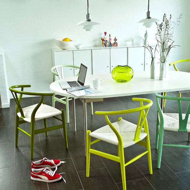 Colorful dining chairs in lime green, mint green, and white, with a minimalist white table and vibrant decor accents.