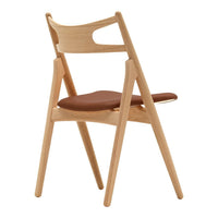 Light wood folding chair with a smooth tan leather seat, featuring a minimalist design and natural hues.