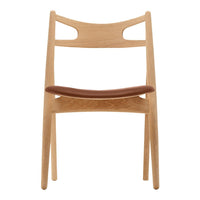 Natural wood chair with a light oak finish and a rich brown leather seat, featuring a minimalist design.